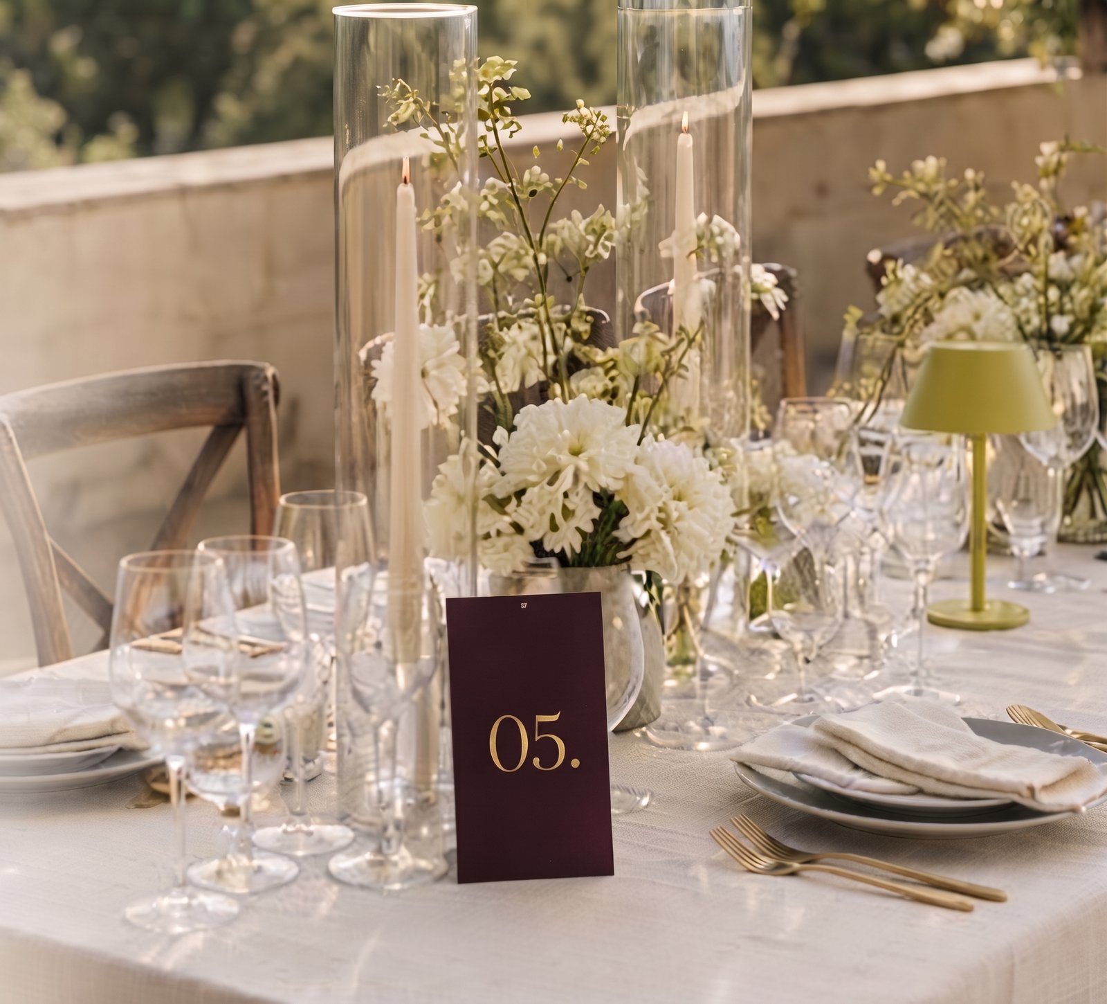 Mesa de banquete con copas, velas altas y número de mesa 05 en tarjeta vino